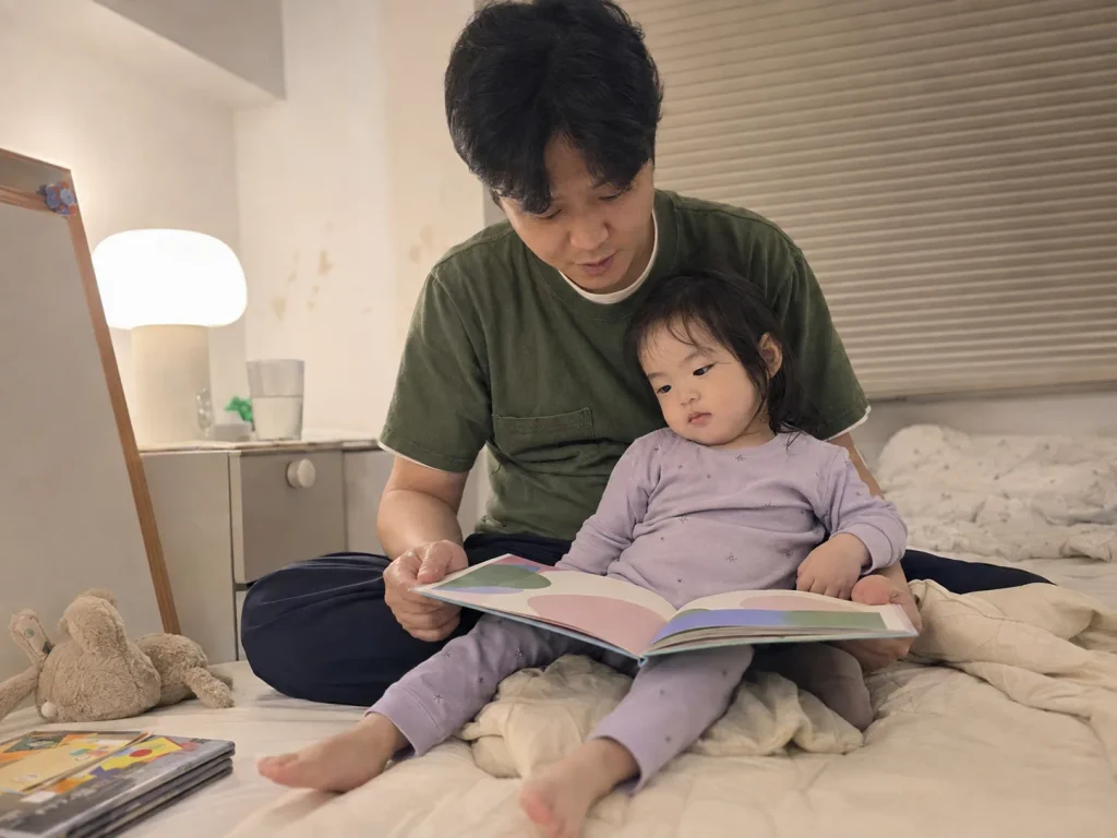아빠 품에 앉아 그림책을 함께 보는 아이