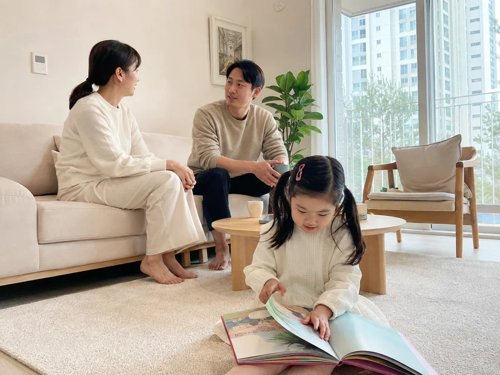 거실에서 편안하게 쉬는 가족과 책 읽는 아이