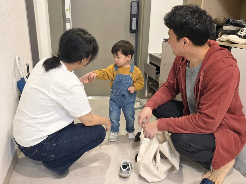 현관에서 엄마가 인사하고 나가려 할 때 아빠와 함께 있는 아이