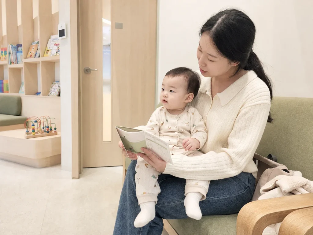 병원 대기실에서 아기를 안고 예방접종을 기다리는 엄마