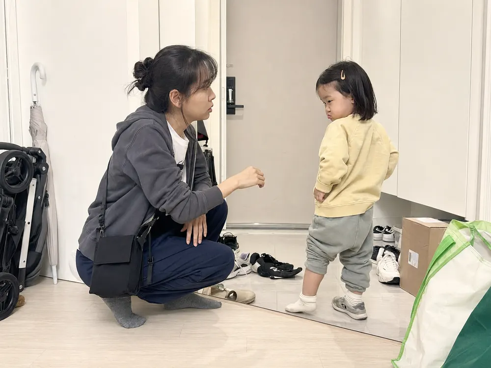현관에서 아이 눈높이로 앉아 짧게 말하는 엄마