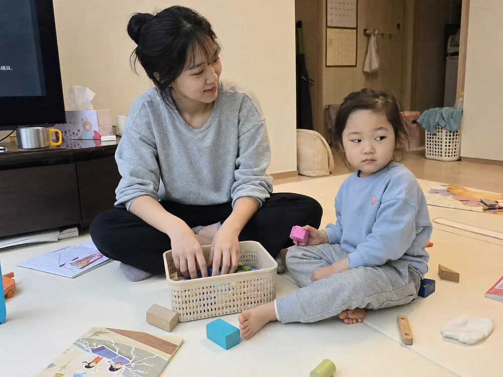 바구니에 블록을 함께 담으며 정리를 시작하는 엄마와 아이