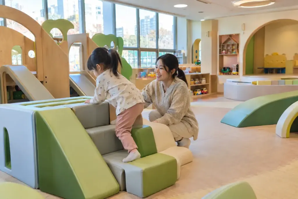아이사랑놀이터 자유놀이실에서 미끄럼틀을 오르는 아이와 엄마