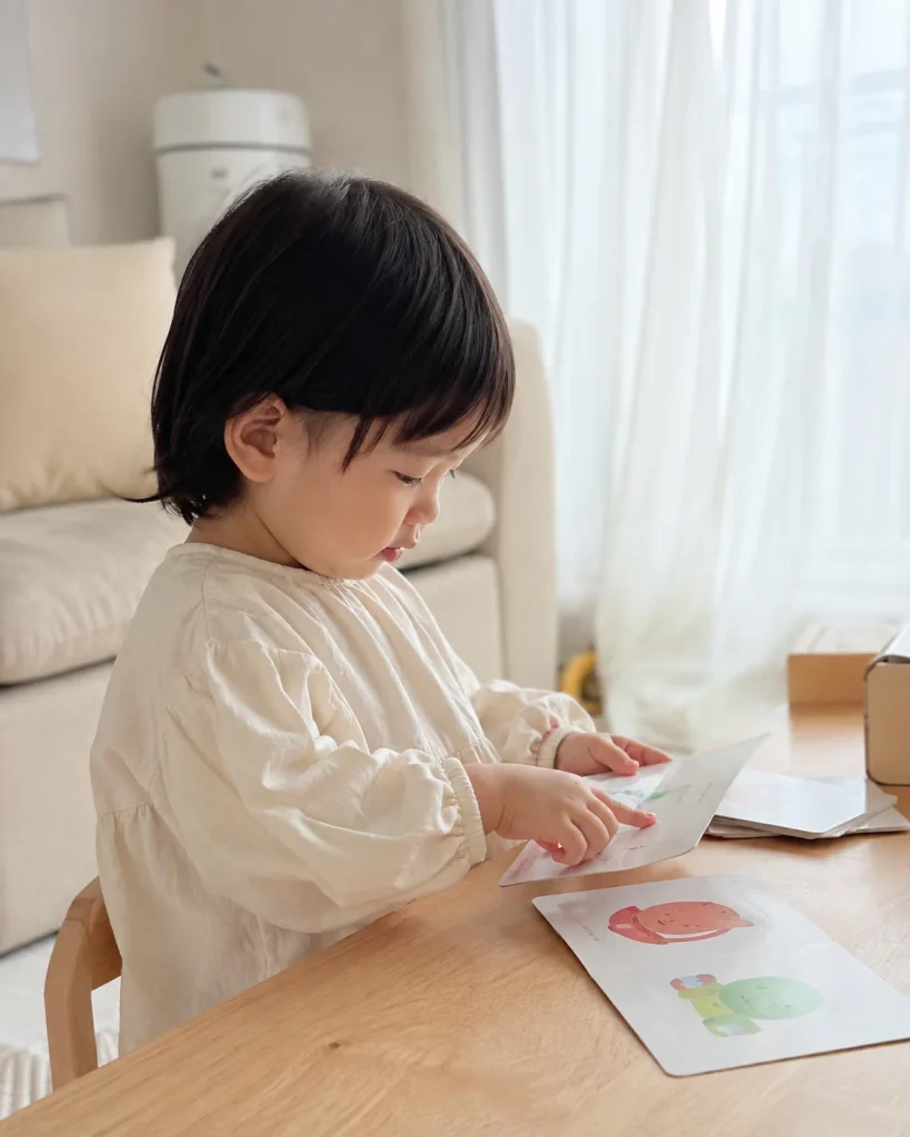 테이블에서 그림 카드를 가까이 들여다보는 아이