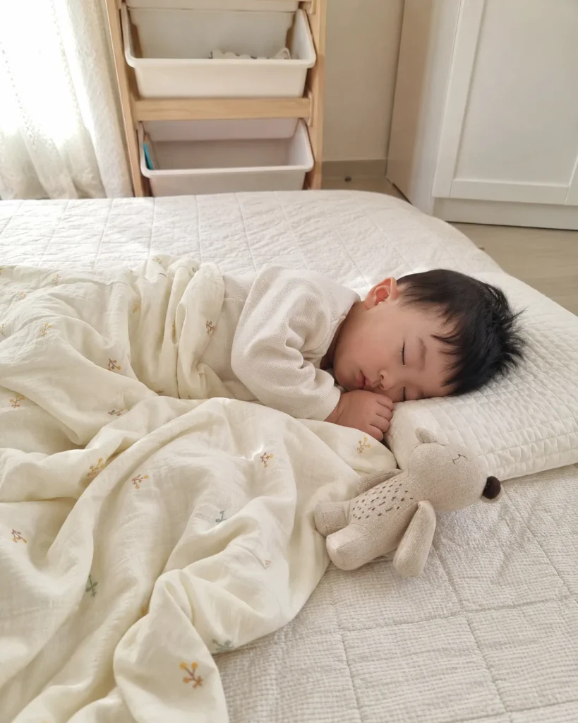 침대에서 이불을 덮고 낮잠 자는 아이