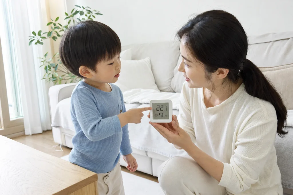 온습도계를 들고 아이와 함께 방 온도를 확인하는 엄마
