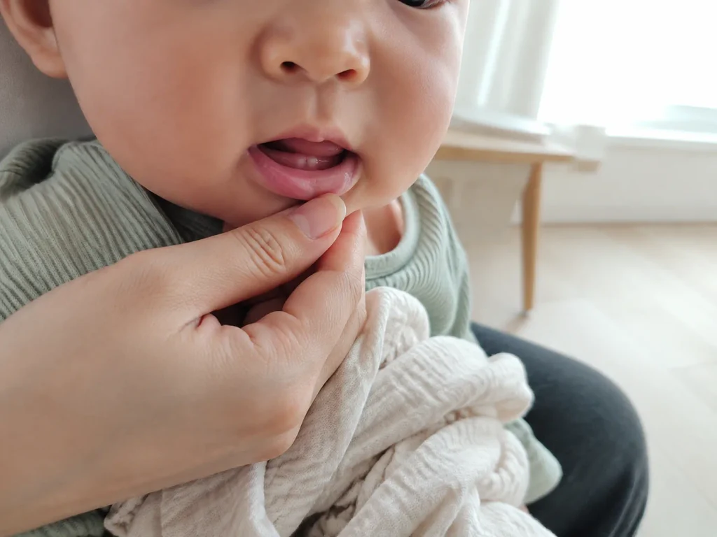 아기 잇몸과 첫니를 손으로 확인하는 모습