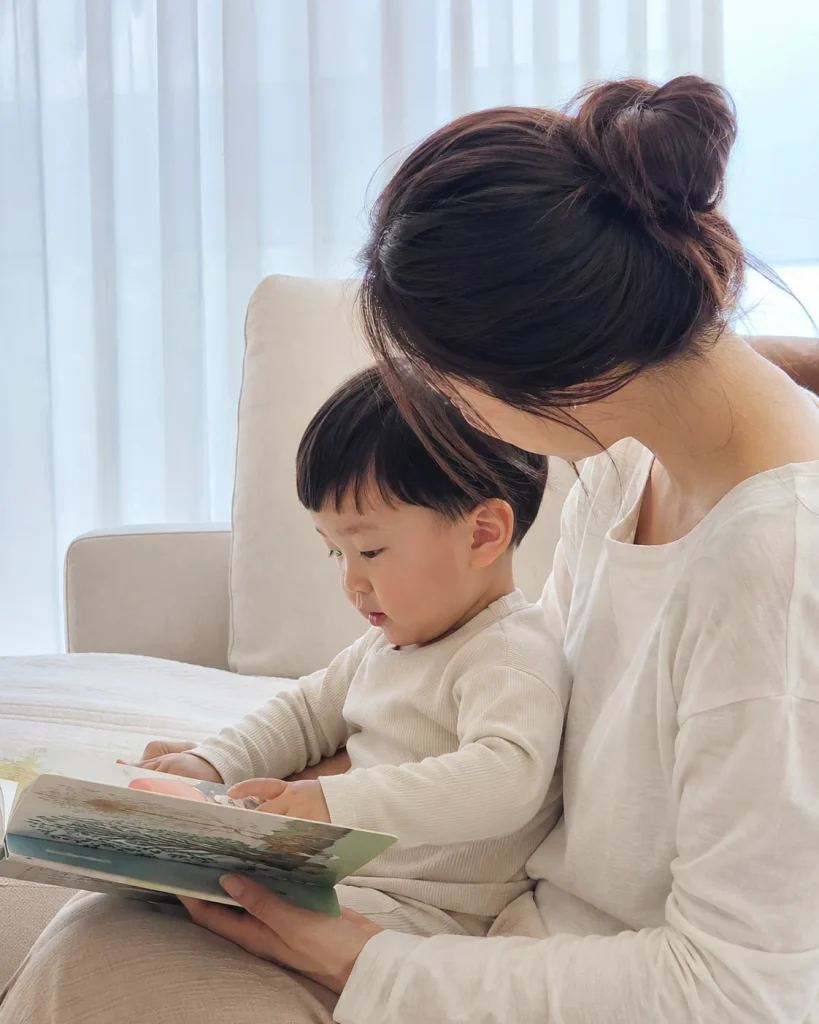 엄마 품에 안겨 그림책을 보는 아이