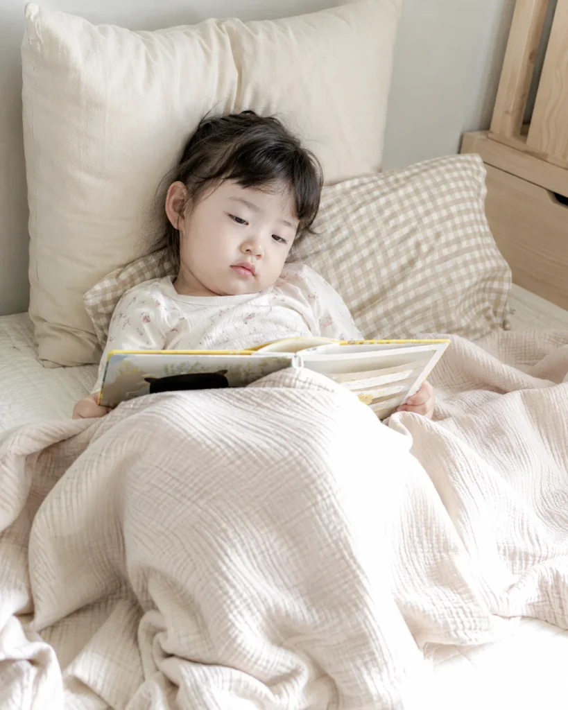 침대에서 책을 보며 조용히 휴식하는 아이